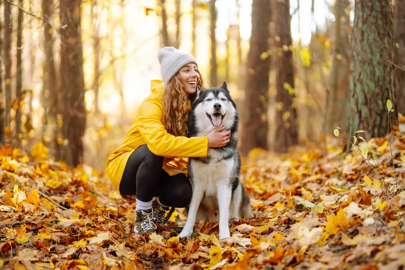 Woman with dog in fall forest 